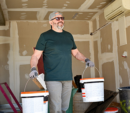 Construction worker carrying buckets of drywall mud
