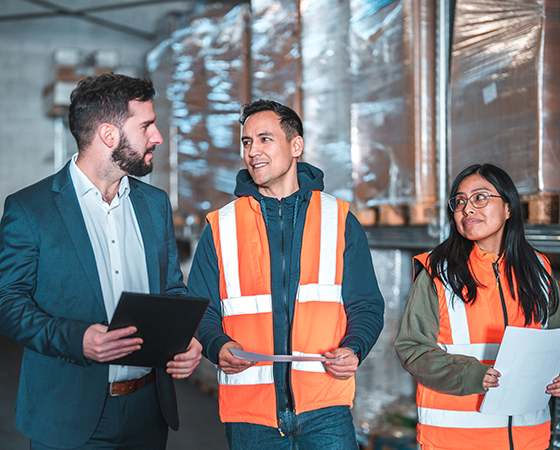 A professional man in a suit having a conversation with two people in construction uniforms.