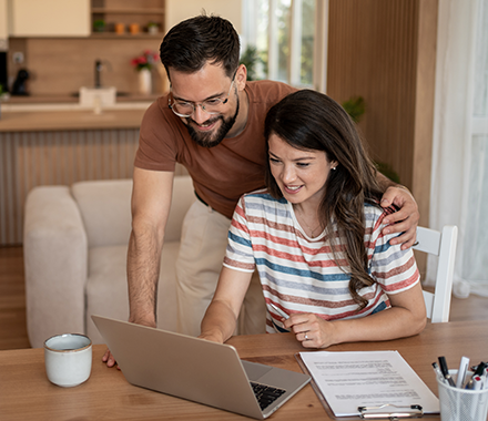 30s couple looking at their finances on their laptop at their kitchen table