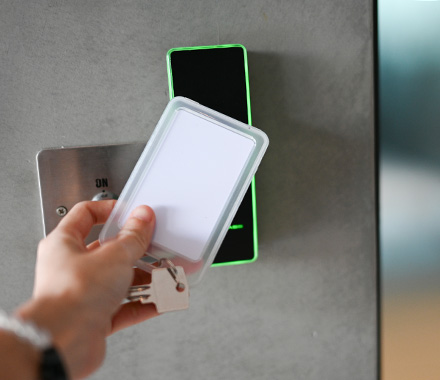 Person using an access card at a security reader, representing physical security and controlled access.