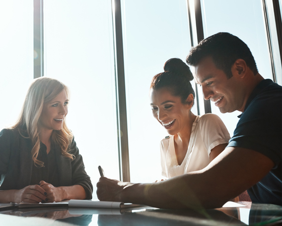 Three happy people signing documents at a table