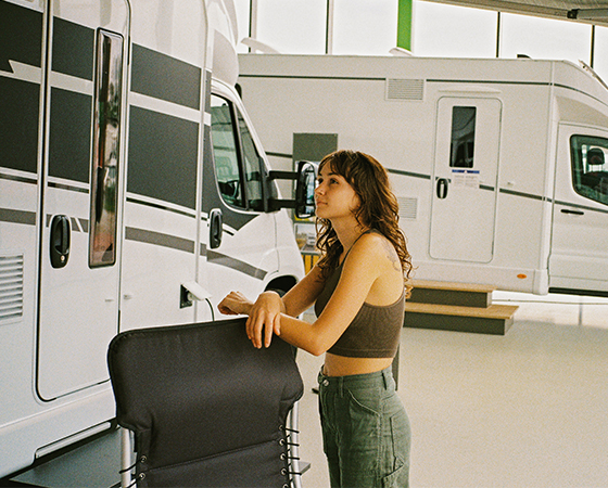 Woman standing beside an RV at a dealership.